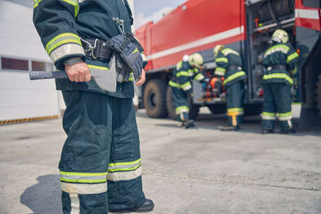 Cropped head of firefighter holding equipment in hand in front of his teamの写真素材