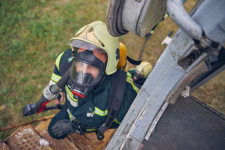 Top view portrait of firefighter in safe helmet going up on stairs with full equipmentの写真素材