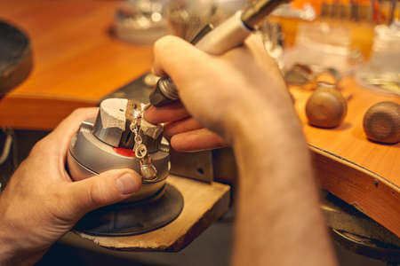 Cropped photo of a skilled craftsman using a metal instrument for making a boxing glove keychainの写真素材