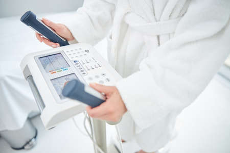 Woman holding her arms on dashboard medical equipment for allow the bioelectric currents to pass...