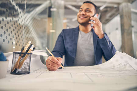 Cheerful international man expressing positivity while being in all ears during telephone talk