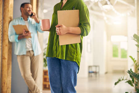 Young female person wearing bright clothes while going to meeting hall with folder in her handの写真素材