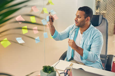 Attentive brunette looking at his notes while sitting at his workplace