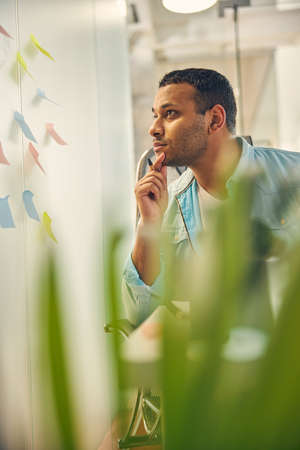 Kind brunette man being deep in thoughts while creating plan of his project presentation