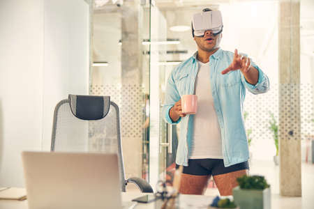 Cheerful international man pointing at something while testing mask for virtual vision