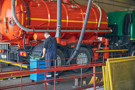 Kind male person wearing uniform and bowing his head while choosing necessary screw key