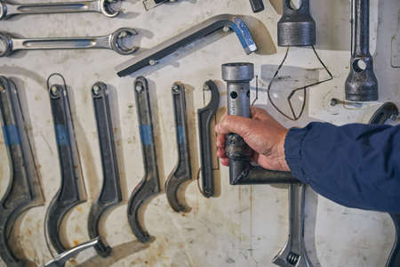 Close up of professional mechanic wearing uniform while working in hangar repairing technic
