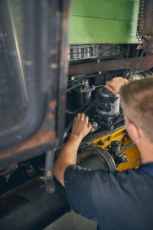 Concentrated male person being in workshop while doing diagnostic of motor vehicleの写真素材