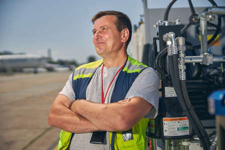 Kind brunette male expressing positivity, crossing arms on chest and looking upwards at skyの写真素材