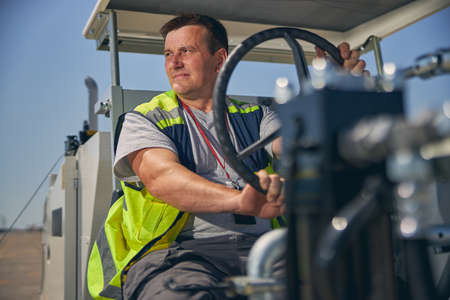 Cheerful male person being deep in his thoughts while working as driver at the airport