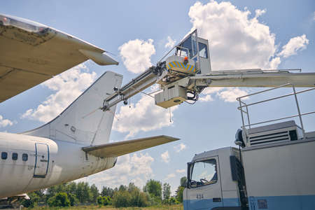 Focused photo on truck crane being on the foreground, standing near aircraftの写真素材