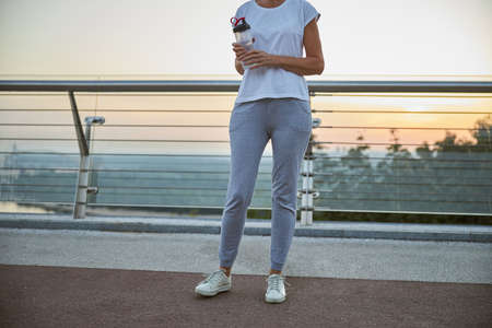 Cropped photo of a fit woman holding a plastic bottle of water in her hand