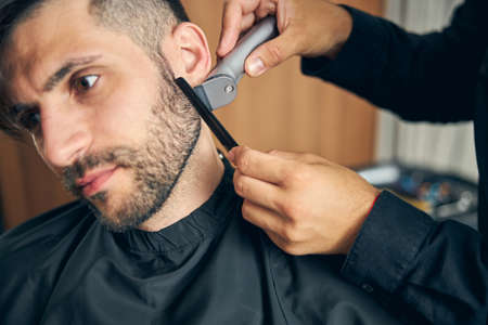 Close up of handsome male bowing his head while visiting barbershopの写真素材