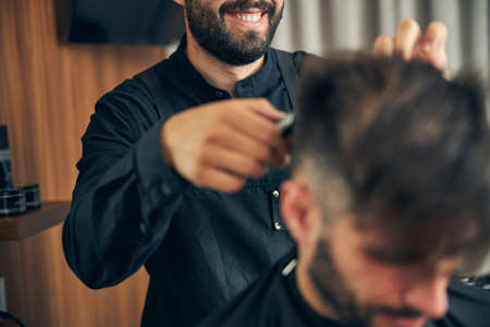 Professional barber expressing positivity while talking to his client during beauty procedureの写真素材