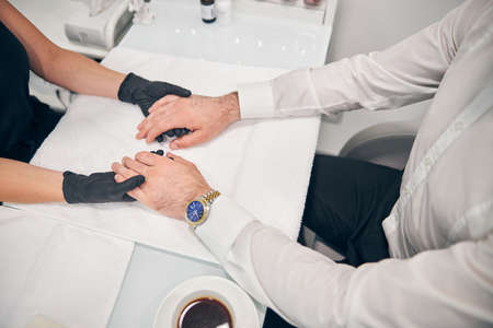 Focused photo on young man sitting in semi position and waiting for beauty procedureの写真素材