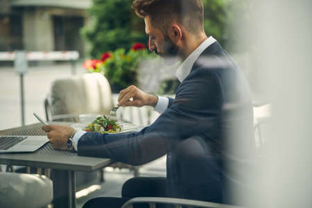 Profile photo of handsome male person that sitting in semi position and enjoying his lunch