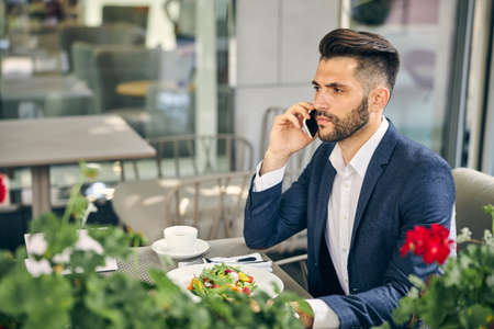 Kind brunette man sitting at the table and going to have dinner outdoors on the terraceの写真素材