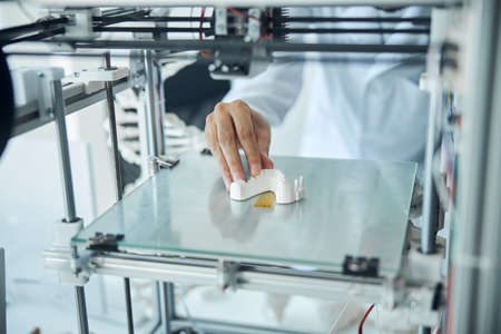 Cropped photo of a medical student in a lab coat examining the 3D printed dentureの写真素材
