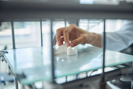 Cropped photo of a male scientist examining the 3D printed denture on the build platformの写真素材