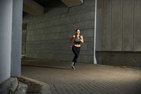 Cheerful young woman keeping smile on her face while doing sport with great pleasure
