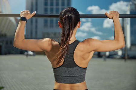 Strong female person wearing uniform while doing sport alone, keeping her body fit