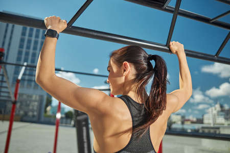 Pleased strong woman demonstrating her power, having training outdoors in the yard