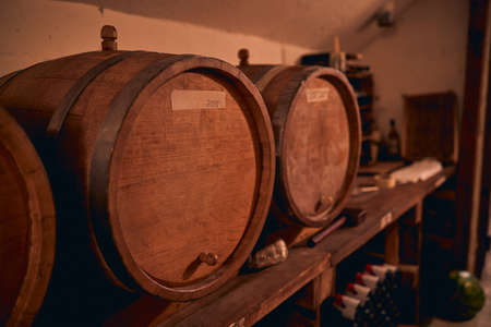 Close up of wooden wine barrels or casks with year paper label in wine cellarの写真素材