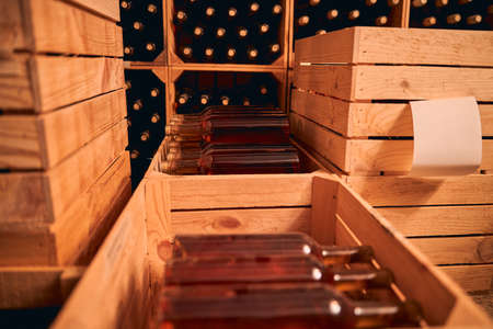 Wine cellar or storage room with bottles of alcoholic drink in wooden boxes and wine racks