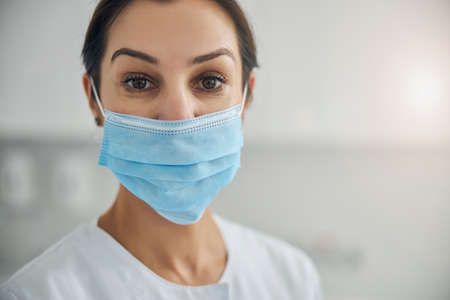 Close up portrait of a serious dark-haired mature Caucasian female dermatologist wearing a...