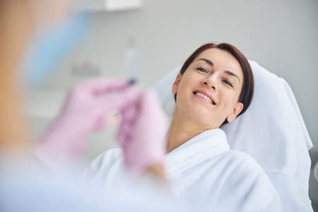 Pleased spa client gazing at a doctor in latex gloves standing in front of herの写真素材