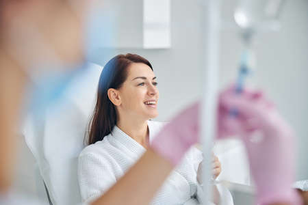 Beautiful middle-aged woman with a beaming smile undergoing the intravenous vitamin therapy in a clinicの写真素材