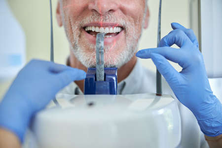 Cropped photo of an elderly patient smiling widely with a bite blocker in his mouth while having his teeth x-rayedの写真素材