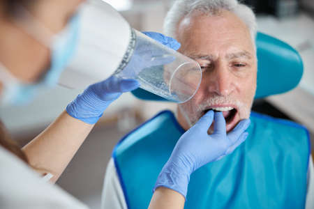 Elderly man sitting down and having his mouth open while going through a procedure of dental-ray