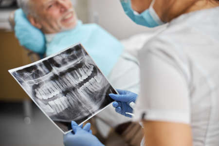 Cropped-up photo of an x-ray image of jaws being held by a professional dental specialist