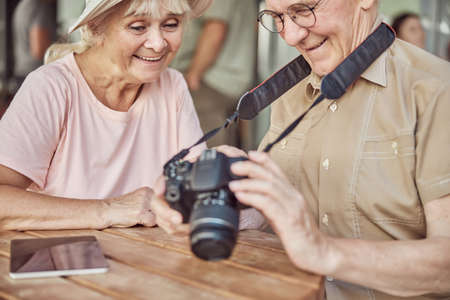 Pleased elderly lady in a sunhat and her husband viewing photos on the digital cameraの写真素材