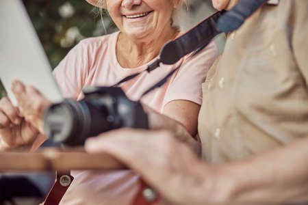 Cropped photo of a smiling woman with a tablet computer sitting by a man with a digital cameraの写真素材
