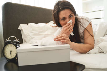 Diseased young Caucasian woman with a paper tissue in her hand looking in front of her