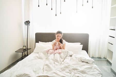 Front view of a sad dark-haired lady looking at a polo shirt in her handsの写真素材