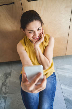 Beautiful dark-haired young Caucasian female with a happy smile photographing herself with the...