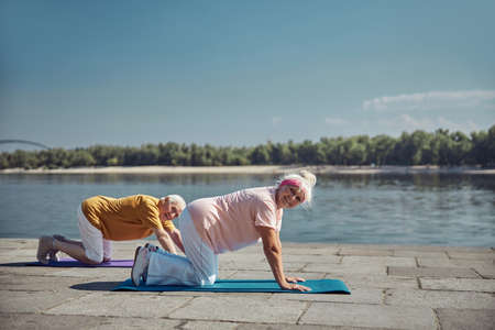 High-spirited elderly Caucasian woman and a man posing for the camera during the yoga workoutの写真素材