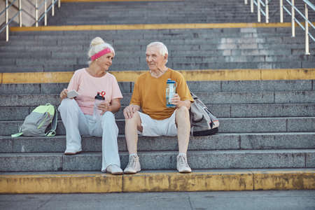 Front view of a male pensioner and his attractive elderly wife sitting on the stairs
