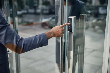 Kind dark-skinned man standing close to the door while trying to enter the buildingの写真素材