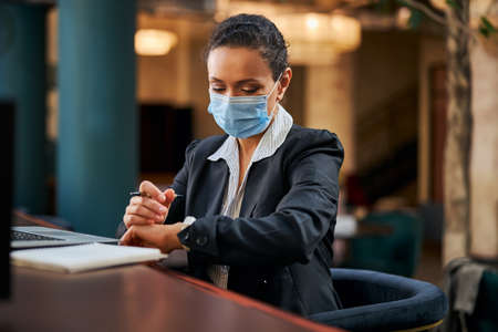 Serious businesswoman being in cafe and checking time while waiting for meetingの写真素材