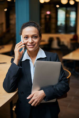 Positive delighted brunette holding laptop while going to meet her colleagues