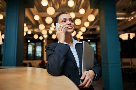 Kind international office worker keeping smile on her face while being in all ears during...