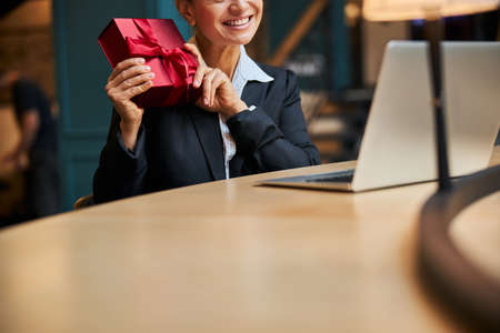 Amazing brunette female person keeping smile on her face while looking at screen of her computerの写真素材