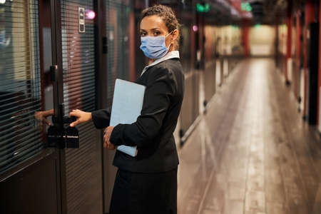 Pleased dark-skinned female person wearing mask while following the rules of quarantine