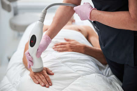 Cropped photo of a beautician performing a non-invasive skin treatment procedure on a hand of a...