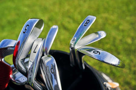 Close up of different types of stainless steel golf clubs with numbers placed in a golfer bagの写真素材