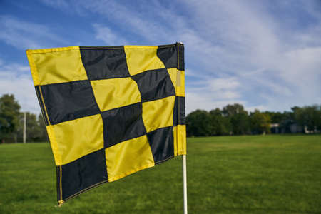 Close up of a golf flagstick marking the location of the hole for players on the sunlit putting...